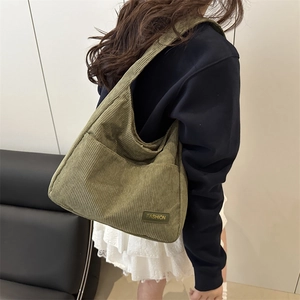 Olive green corduroy tote bag with fashion label shown on a female model shoulder