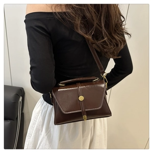 Vue détaillée du sac bandoulière vintage marron foncé avec cuir brillant et boucle dorée