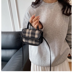 Detail of vintage plaid tweed handbag with leather handle and adjustable shoulder strap