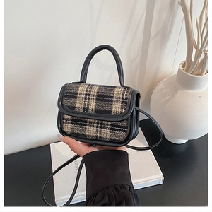 Close-up of retro black and white plaid tweed handbag with leather handles and strap