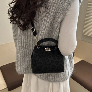 Sac bandoulière noir imprimé léopard avec boucle dorée porté par un mannequin