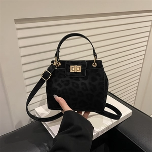 Detail of black leopard print texture and shiny gold square twist lock on handbag