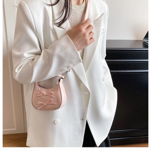 Detail of pink mini half-moon bag with 3D bows shown on model in white blazer