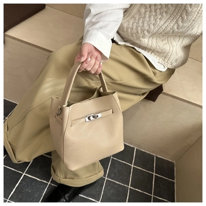 Detailed view of apricot pebbled leather bucket bag with silver twist lock and handle