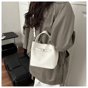 Detailed shot of white lychee pattern bucket bag with silver metal lock and leather handle