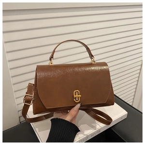 Detail view of brown vintage leather square handbag with golden twist lock and top handle