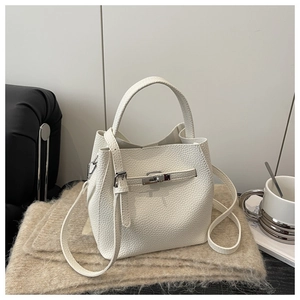 Detailed close-up of white lychee texture leather bucket bag with silver metal swivel lock