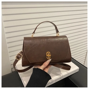 Detailed view of dark brown vintage faux leather bag featuring a gold metal twist lock