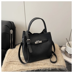 Detailed close-up of black litchi grain leather bucket bag with silver buckle on plush scarf