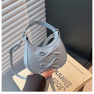Close-up of a light blue mini crescent bag with cute bows and glossy leather finish