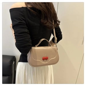 Detail of crossbody bag featuring 3D cherry decor and golden metal hardware