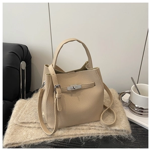 Detail of beige lychee pattern leather bucket bag with silver twist lock and strap