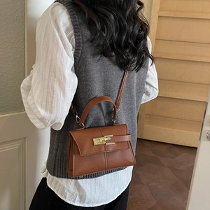 Classic brown crossbody bag with lychee texture and metal twist lock shown on a model