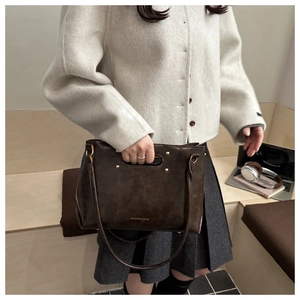 Detail of vintage brown leather bag showing hollow handles and fashion logo print