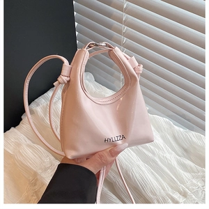Detail of light pink mini handbag with glossy finish, hollow handle, and HYLLZZA branding