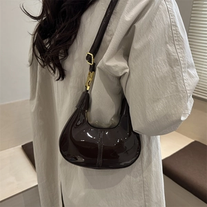 Sac croissant chic en cuir verni marron foncé avec détails dorés et bandoulière réglable