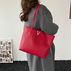 Minimalist red leather tote bag with gold V logo shown as a stylish shoulder bag