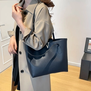 Large black leather tote bag with gold V-detail, minimalist shoulder bag for daily commuting