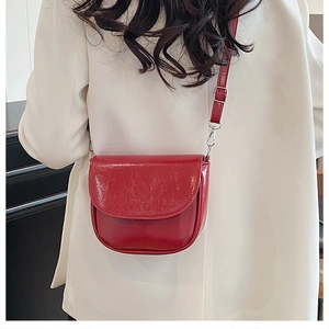 Détail du sac selle en cuir rouge brillant porté par un mannequin en veste