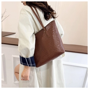 Close-up detail of dark brown tote bag featuring intricate woven texture and leather straps