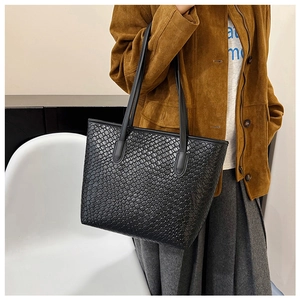 Close-up of black woven tote bag texture featuring intricate square knit detail and straps