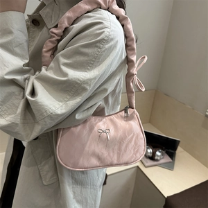 Pink pleated underarm cloud bag with silver metal bow and ruffles in a lifestyle setting