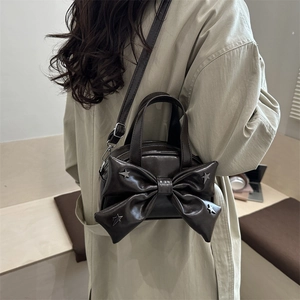 Dark brown leather bucket bag with large bow and silver star studs in a lifestyle setting