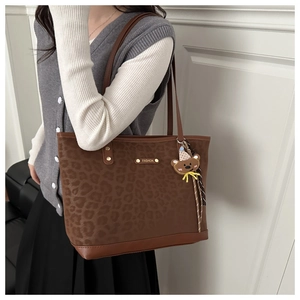 Close-up of leopard print tote bag featuring a cute bear charm and FASHION metal plate