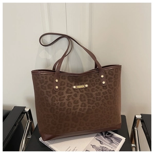 Close-up of leopard print tote bag featuring a gold fashion plaque and metal rivets