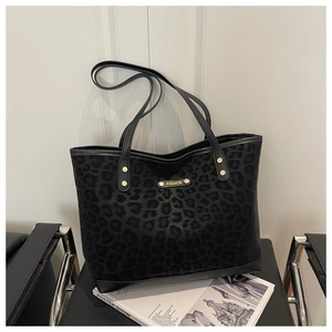 Detail of black leopard print tote bag with matte texture and gold fashion plaque