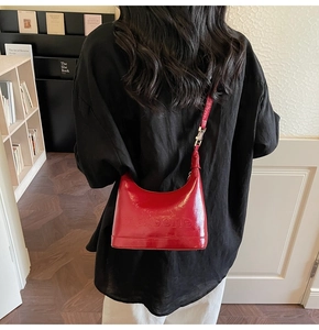 Close-up of red patent leather Hobo bag with embossed letters and silver hardware