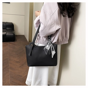 Close-up of black litchi grain leather tote bag handle with a decorative silk scarf detail