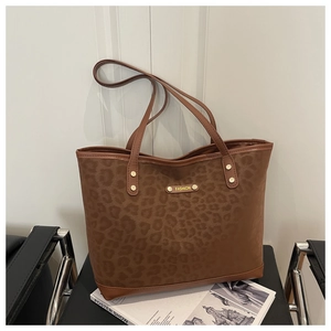 Close-up of leopard print tote bag with metallic fashion logo on synthetic leather
