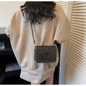 Detail of black crossbody bag with white contrast stitching and unique horn buckle