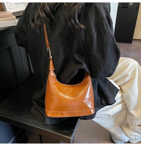 Detail showing brown vintage dumpling bag with Maisone embossing and pleated leather texture