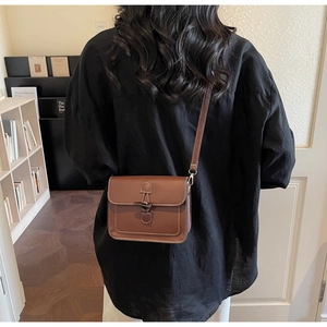 Detail view of a vintage brown crossbody bag with toggle closure on a model