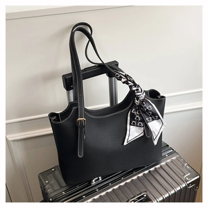 Detail of black pebbled leather tote bag with white stitching and printed silk scarf
