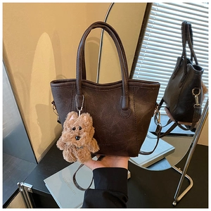 Detail of a dark brown vintage bucket bag with plush toy dog charm and leather texture