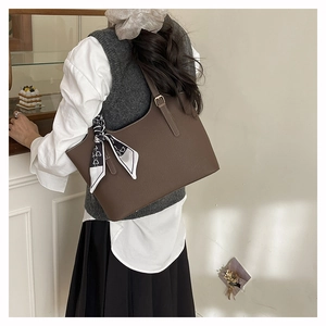 Brown lychee leather tote bag with silk scarf detail shown on shoulder in room