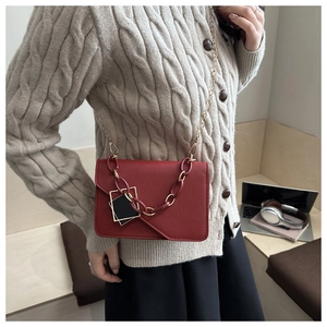 Red retro leather crossbody bag styled with a textured chain and gold metal strap detail
