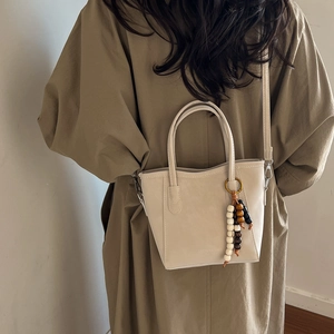 Elegant cream white bucket bag with beaded tassel charm and detachable shoulder strap