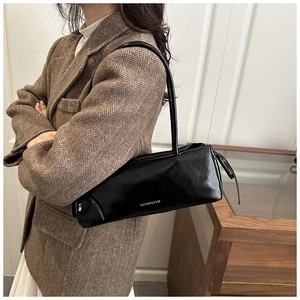 Detailed view of the black glossy leather texture and silver lettering on the shoulder bag