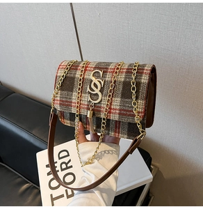 Détail du sac bandoulière à carreaux rouges avec pompon doré et finitions métalliques