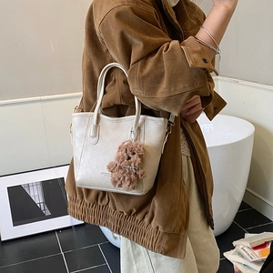 Minimalist white bucket bag in lychee pattern PU leather with a cute bear charm