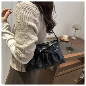 Détail du sac à bandoulière plissé noir avec nœud en cuir et boucle étoile argentée