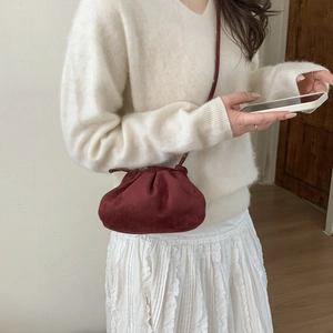 Minimalist dark red dumpling crossbody bag shown on a model with white knitwear