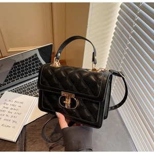 Detail of black quilted handbag featuring a golden turn-lock closure and leather strap