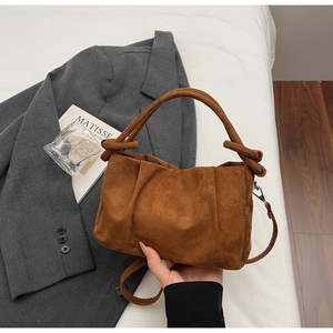 Detailed view of dark brown suede handbag with unique knot handle and textured folds