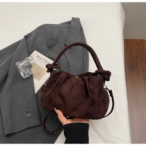 Detail of dark brown suede pleated bag featuring knot handles and silver metal hardware