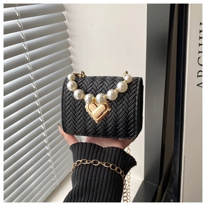 Detail of woven black mini bag featuring a pearl handle and heart-shaped gold clasp